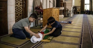 Kinan Abou Haikal (L), the elder brother of seven-month-old baby Sam Fahd Abou Haikal, killed by Israeli gunfire, sits next to his body at the Abou Heisheh Mosque in Hebron, in the occupied West Bank, Palestine, June 6, 2026. (AFP Photo)