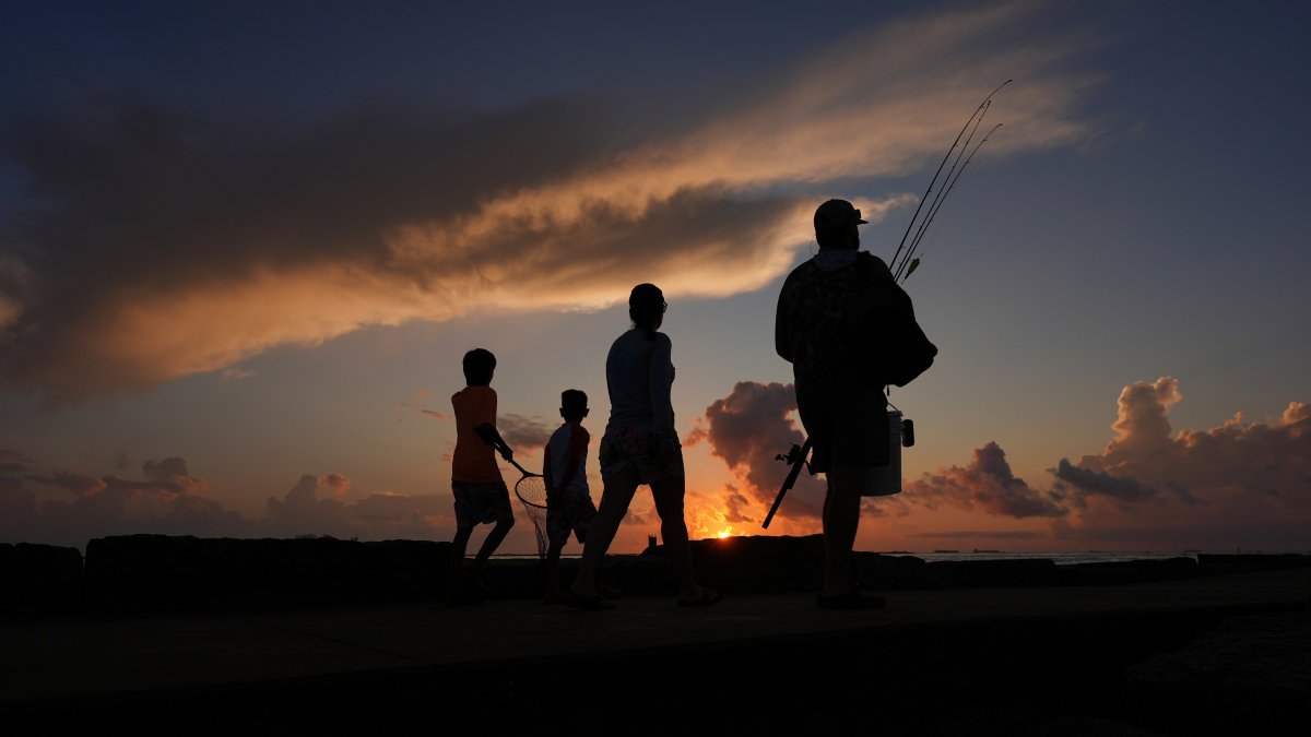 A family prepares to fish along a jetty at sunrise in Port Aransas, Texas, U.S., Aug. 10, 2025. (AP Photo)