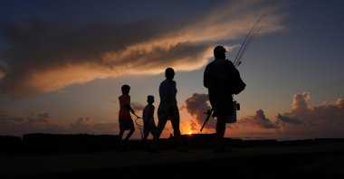 A family prepares to fish along a jetty at sunrise in Port Aransas, Texas, U.S., Aug. 10, 2025. (AP Photo)