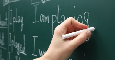 An English teacher writes on a board during a lesson at school. (Shuttterstock Photo) 