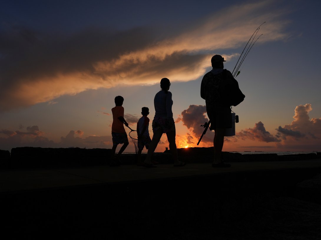 A family prepares to fish along a jetty at sunrise in Port Aransas, Texas, U.S., Aug. 10, 2025. (AP Photo)