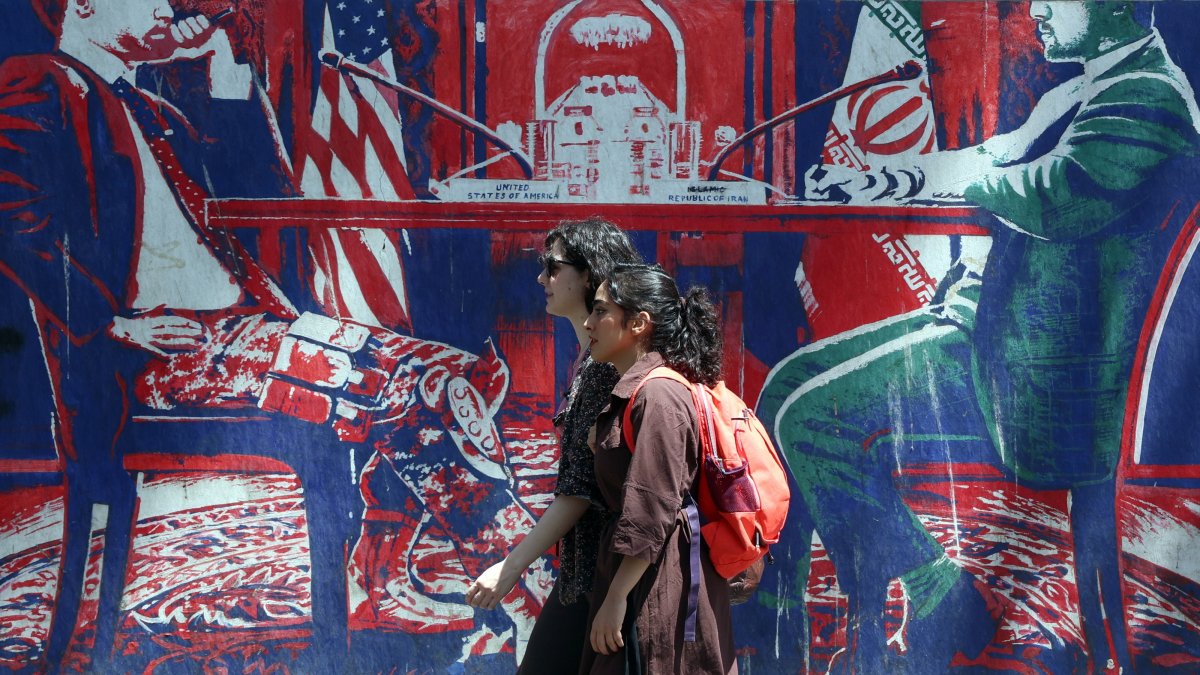 Iranian girls walk past an anti-U.S. mural next to the former U.S. embassy in Tehran, Iran, June 22, 2026. (EPA Photo)