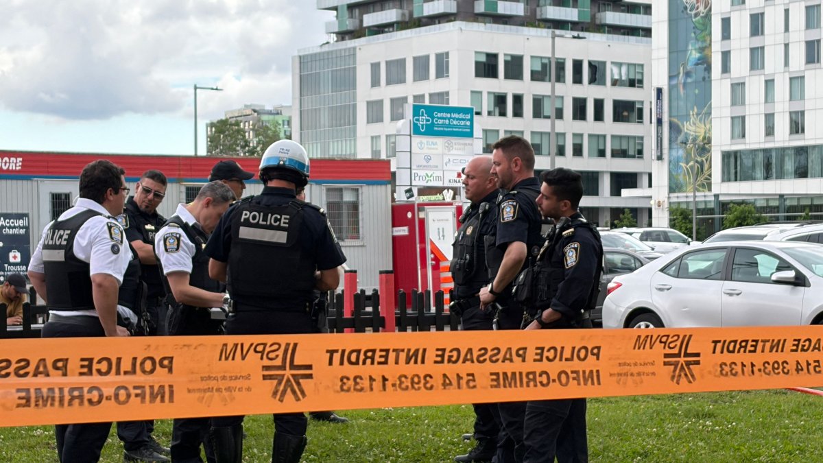 Damaged windows can be seen in the distance as police gather near the scene of a shooting in Montreal, June 22, 2026. (AFP Photo)