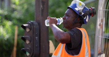 A worker drinks water at a construction site as temperatures rise during a heatwave, Paris, France, June 22, 2026. (Reuters Photo)