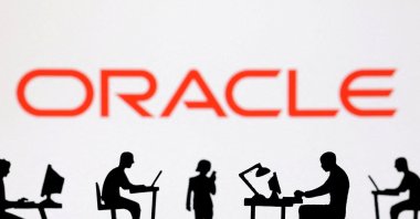 Figurines with computers and smartphones are seen in front of the Oracle logo in this illustration taken on Feb. 19, 2024. (Reuters Photo)