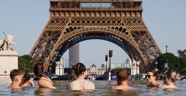 People cool off in the Trocadero Fountain next to the Eiffel Tower as temperatures rise during a heatwave affecting a large part of the country, Paris, France, June 22, 2026. (Reuters Photo)