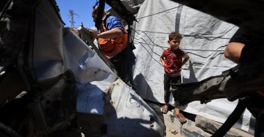 A child looks on as Palestinians inspect a vehicle hit in an Israeli strike, Gaza City, Palestine, June 18, 2026. (Reuters Photo)