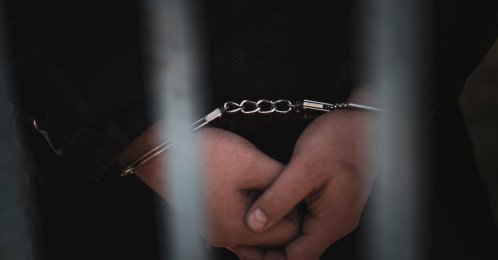 A suspect in handcuffs is seen at a courthouse. (Shutterstock Photo) 