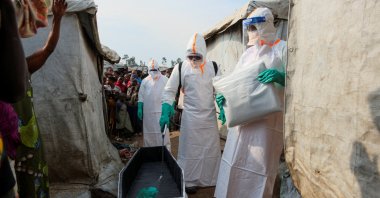 Health workers in full personal protective equipment (PPE) disinfect a coffin while preparing for the burial of suspected Ebola victims at the Kigonze displaced persons camp, Bunia, DRC, June 18, 2026. (Reuters Photo)
