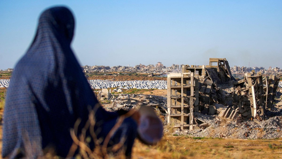 A woman sits along a promontory overlooking shelters for people displaced by war near a heavily damaged building at the Nuseirat camp for Palestinian refugees, Gaza Strip, Palestine, June 19, 2026. (AFP Photo)
