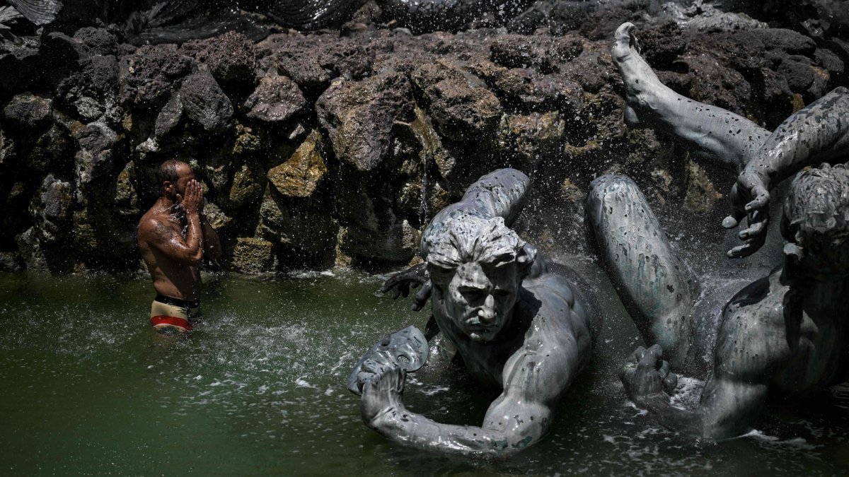 A man cools off in the basin of the Girondins Fountain at Place des Quinconces as France experiences a heatwave, in Bordeaux, southwestern France, June 22, 2026. (AFP Photo)