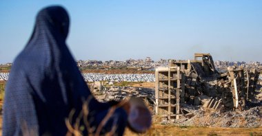 A woman sits along a promontory overlooking shelters for people displaced by war near a heavily damaged building at the Nuseirat camp for Palestinian refugees, Gaza Strip, Palestine, June 19, 2026. (AFP Photo)