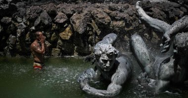 A man cools off in the basin of the Girondins Fountain at Place des Quinconces as France experiences a heatwave, in Bordeaux, southwestern France, June 22, 2026. (AFP Photo)