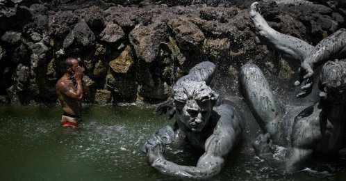 A man cools off in the basin of the Girondins Fountain at Place des Quinconces as France experiences a heatwave, in Bordeaux, southwestern France, June 22, 2026. (AFP Photo)