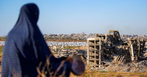 A woman sits along a promontory overlooking shelters for people displaced by war near a heavily damaged building at the Nuseirat camp for Palestinian refugees, Gaza Strip, Palestine, June 19, 2026. (AFP Photo)