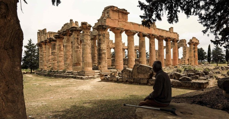 A man sits in the shade in front of the Temple of Zeus at the archaeological site of Cyrene, near the town of Shahat, Libya, May 18, 2026. (AFP Photo)