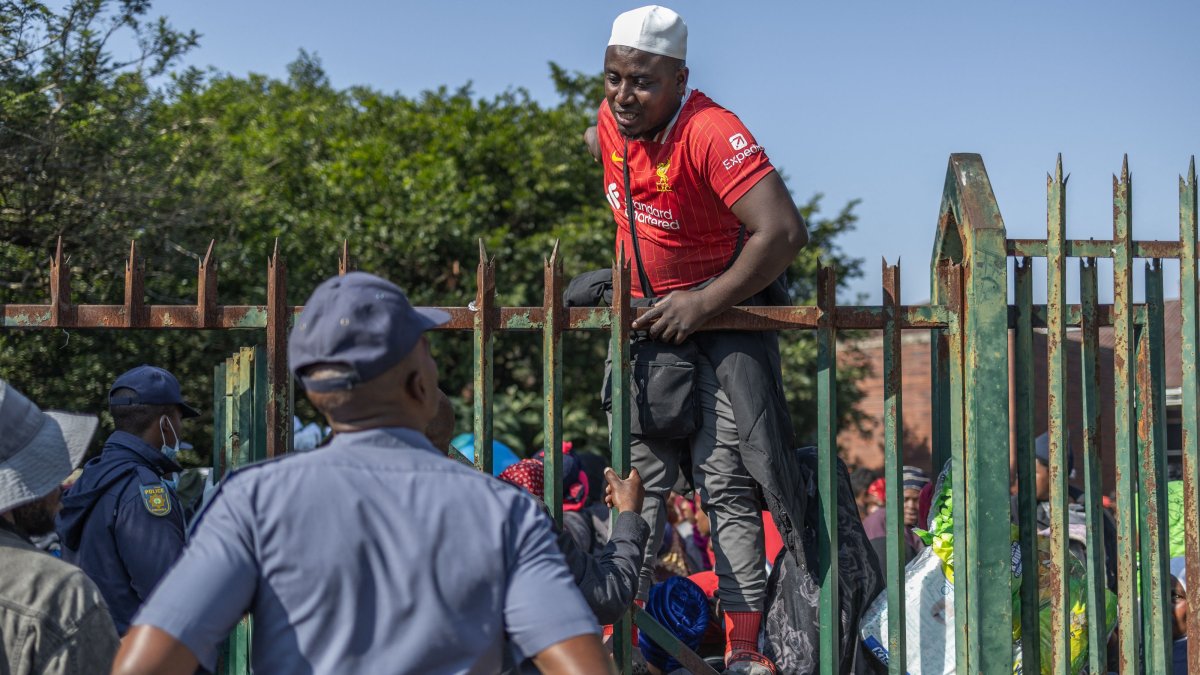 A displaced Malawian national speaks to a member of the South African Police Service (SAPS) while taking shelter at an abandoned municipality building on Mayor’s Walk after fleeing their homes amid fears of xenophobic attacks and threats from anti-illegal immigration groups, Pietermaritzburg, South Africa, June 23, 2026. (AFP Photo)