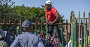 A displaced Malawian national speaks to a member of the South African Police Service (SAPS) while taking shelter at an abandoned municipality building on Mayor’s Walk after fleeing their homes amid fears of xenophobic attacks and threats from anti-illegal immigration groups, Pietermaritzburg, South Africa, June 23, 2026. (AFP Photo)