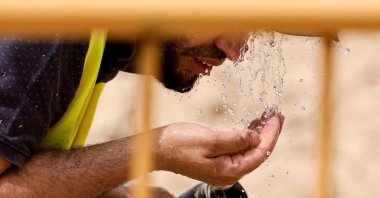 A worker cools off with water at a road construction site during the heat wave affecting the Iberian Peninsula, Madrid, Sapin, June 22, 2026. (AFP Photo)
