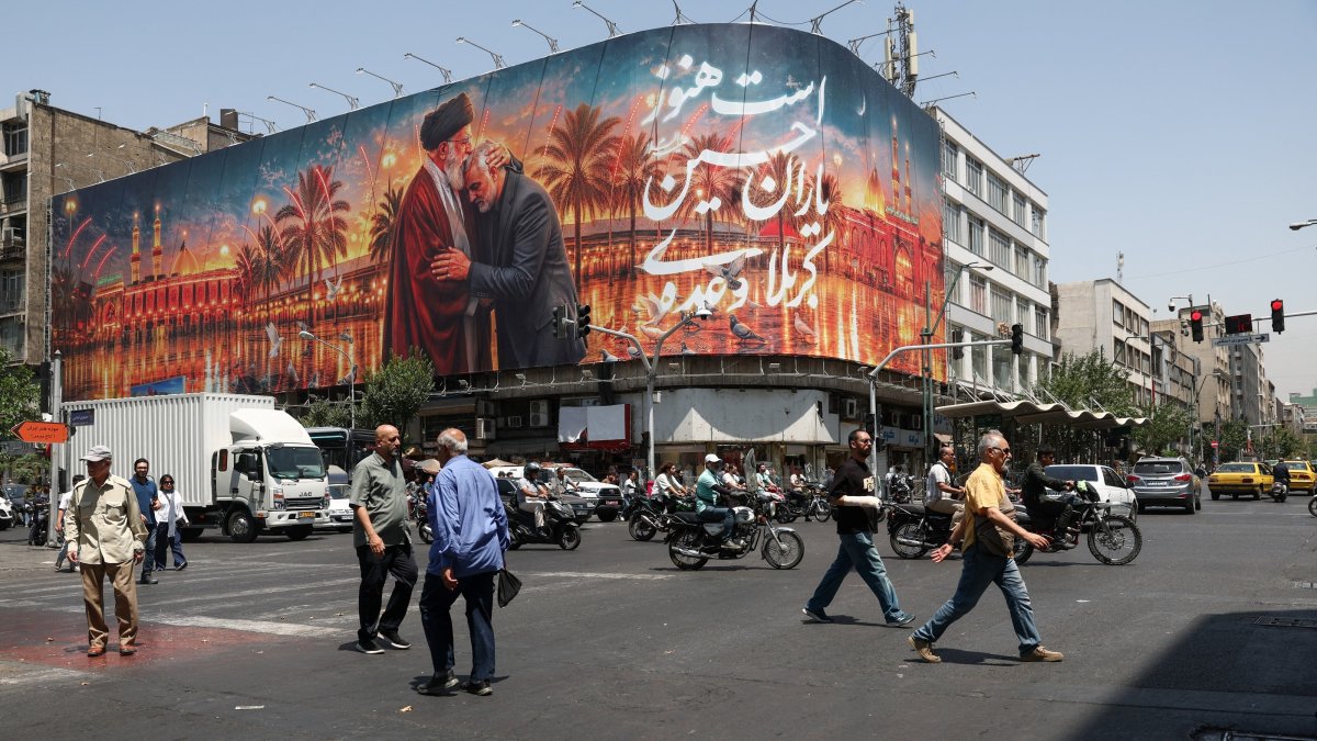 People move past a billboard with an image that depicts Iran's late Supreme Leader Ayatollah Ali Khamenei embracing late senior Iranian military commander General Qassem Soleimani, in Tehran, Iran, June 28, 2026. (Reuters Photo)