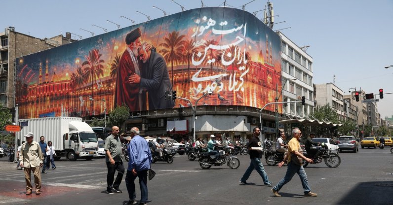 People move past a billboard with an image that depicts Iran's late Supreme Leader Ayatollah Ali Khamenei embracing late senior Iranian military commander General Qassem Soleimani, in Tehran, Iran, June 28, 2026. (Reuters Photo)