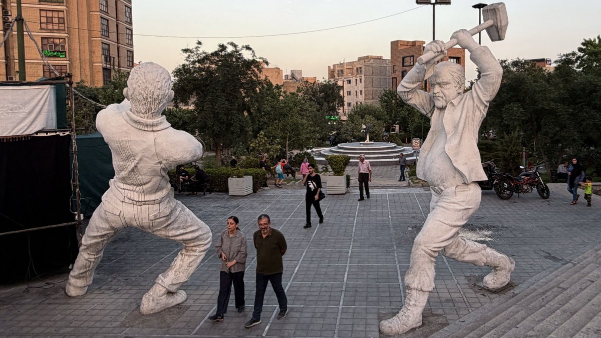 People walk between sculptures of workers in Tehran, Iran, June 22, 2026. (AFP Photo)