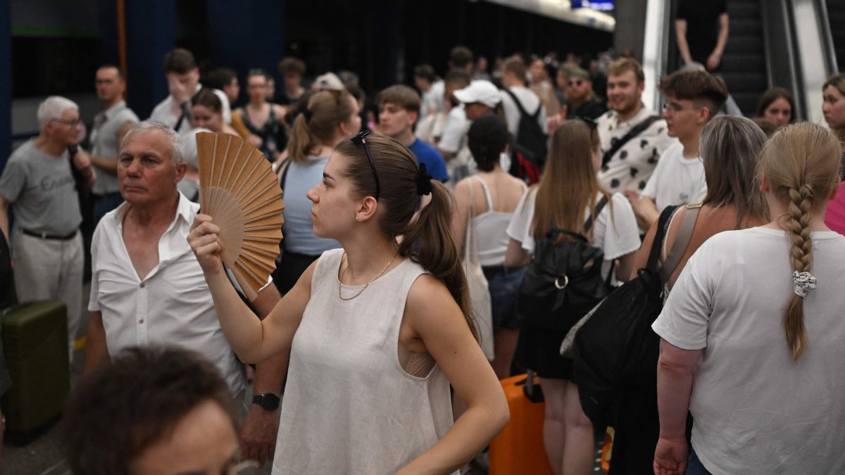 A woman uses a hand fan, waiting for trains delayed due to the heat wave at a railway station in Warsaw, Poland, June 28, 2026. (AFP Photo)