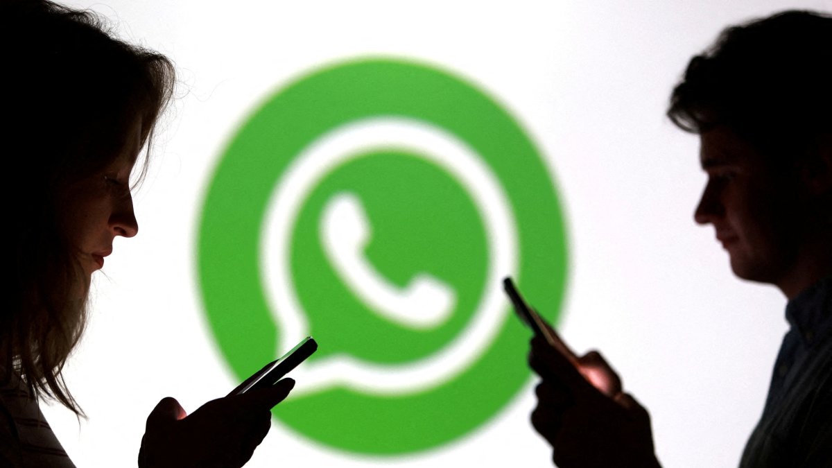 Teenagers pose for a photo while holding smartphones in front of a WhatsApp logo in this illustration taken Sept. 11, 2025. (Reuters File Photo)