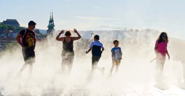 People enjoying the coolness of the water sprayers in the summer heat, Kossuth square, Budapest, Hungary, June 30, 2025. (Shutterstock Photo)
