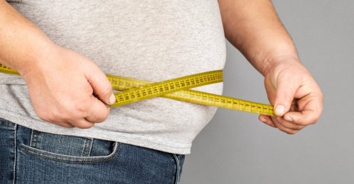 A man measures his belly with a measuring tape. (Shutterstock Photo)