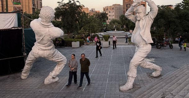 People walk between sculptures of workers in Tehran, Iran, June 22, 2026. (AFP Photo)