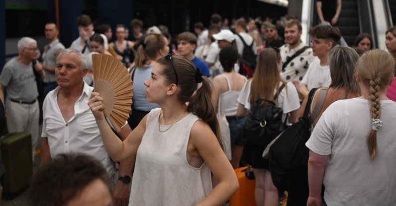 A woman uses a hand fan, waiting for trains delayed due to the heat wave at a railway station in Warsaw, Poland, June 28, 2026. (AFP Photo)