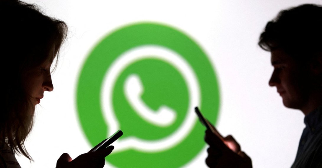 Teenagers pose for a photo while holding smartphones in front of a WhatsApp logo in this illustration taken Sept. 11, 2025. (Reuters File Photo)