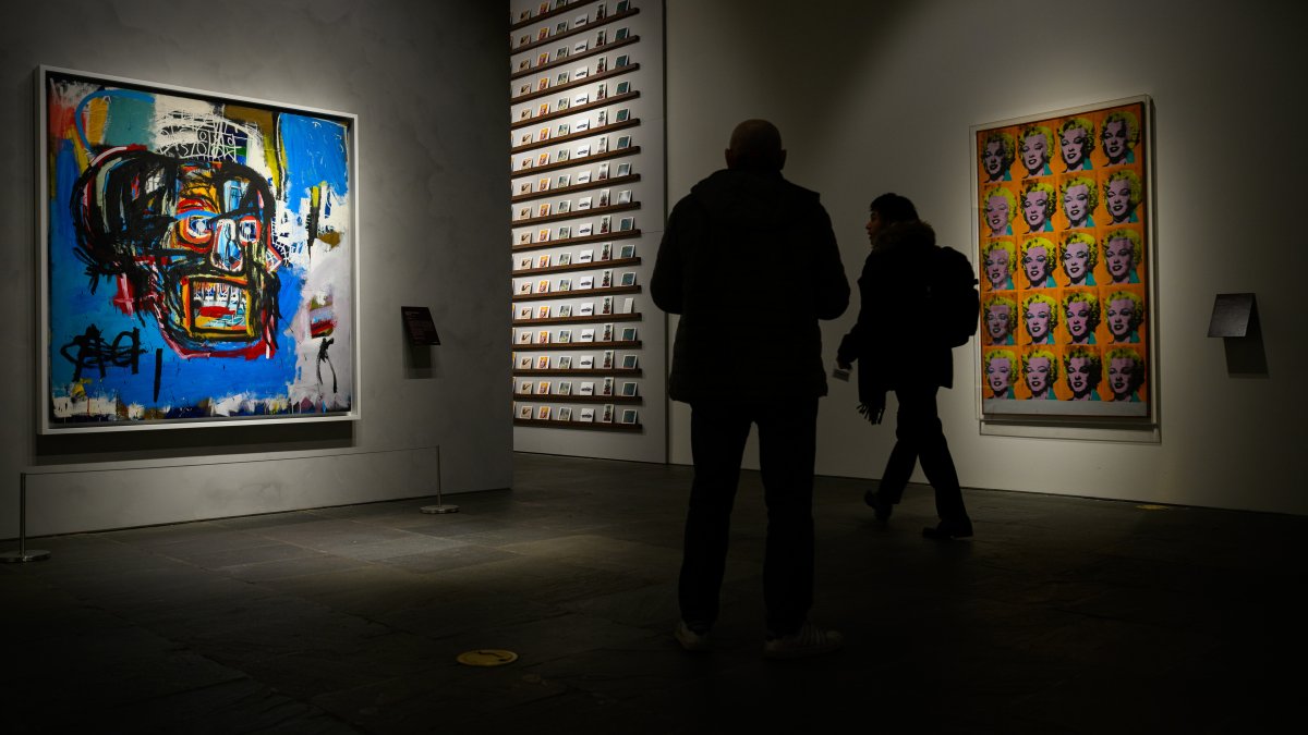 People move past Jean-Michel Basquiat’s Untitled (1982) and Marilyn Monroe (Twenty Times) (1992) (R) by Andy Warhol at Sotheby's Breuer building, New York, U.S., Dec. 13, 2025. (Getty Images Photo)