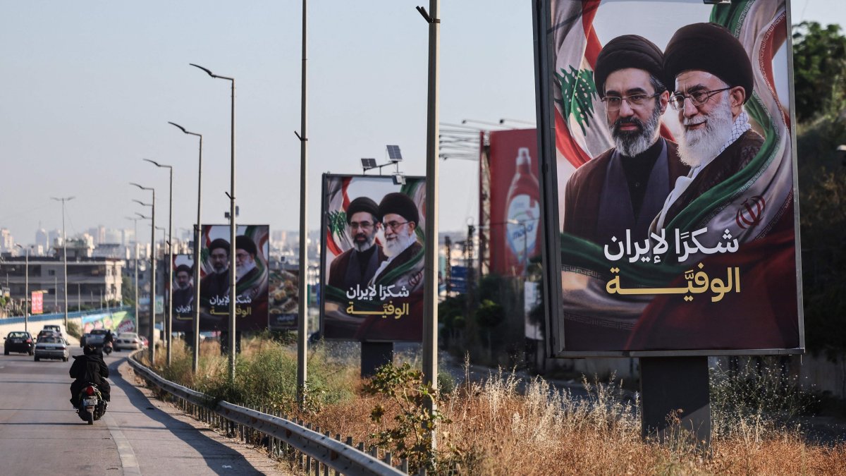 Cars and motorbikes drive past billboards showing Iran’s new Supreme Leader Ayatollah Mojtaba Khamenei (L) and his late father Ali Khamenei (R), with the slogan "Thank you, loyal Iran," erected along the highway leading to Rafic Hariri International Airport in Beirut, Lebanon, June 22, 2026. (AFP Photo)