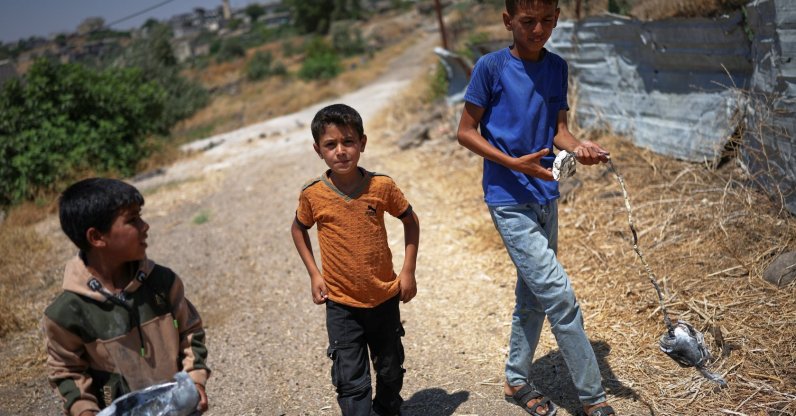 Local boys carry the remains of an exploded Israeli shell in the village of Abdin, Daraa province, Syria, June 29, 2026. (AP Photo)