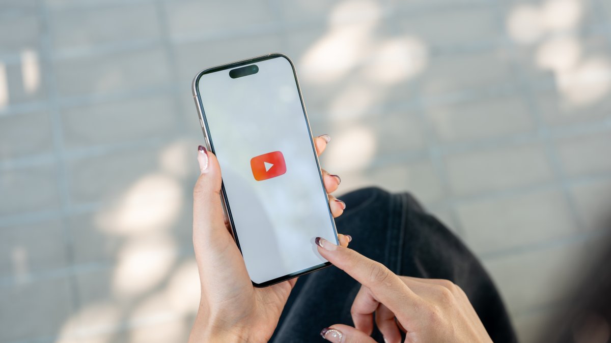 A woman uses the YouTube app on a smartphone. (Shutterstock Photo)