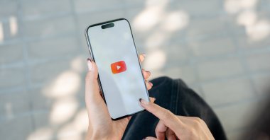 A woman uses the YouTube app on a smartphone. (Shutterstock Photo)