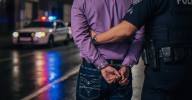 A suspect is escorted by law enforcement officers following an arrest. (Shutterstock Photo)