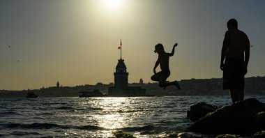 A child jumps into the sea near Maiden’s Tower as people seek relief from warm weather in Istanbul, Türkiye, June 28, 2026. (AFP Photo)