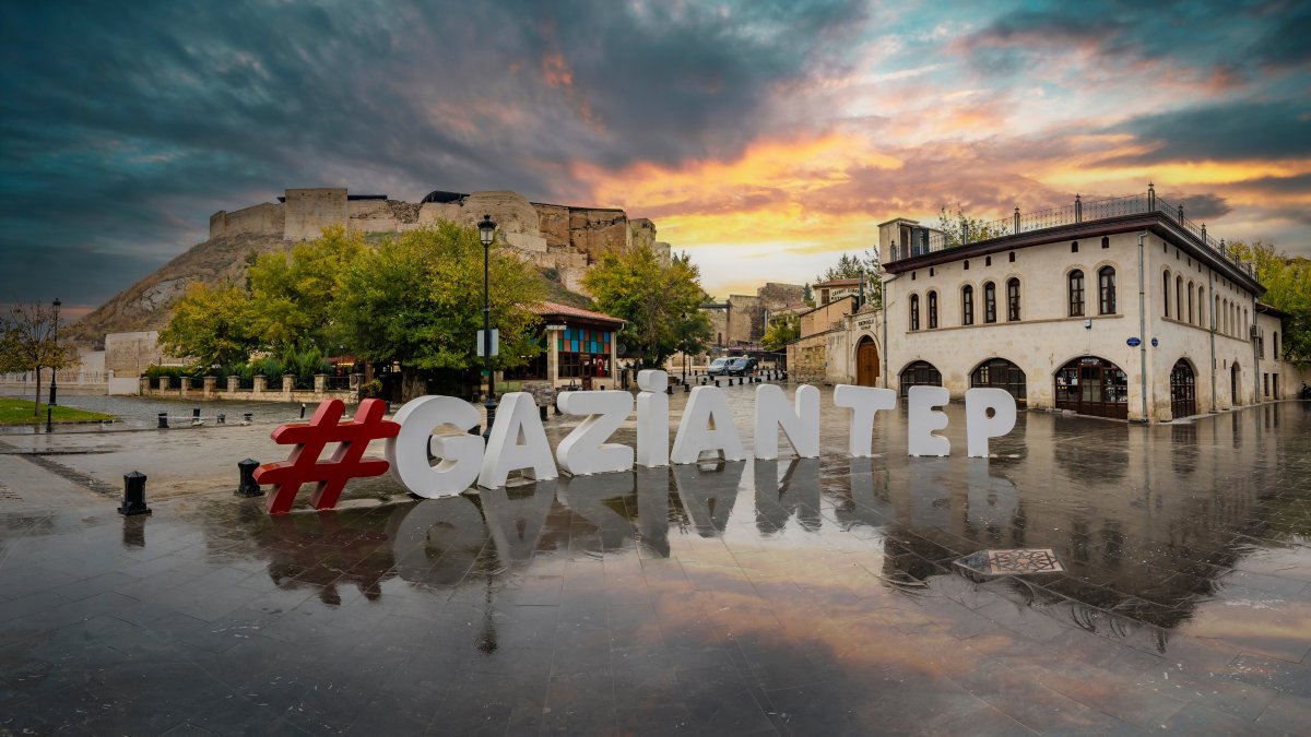 The Gaziantep city logo stands in the foreground with the historic Gaziantep Castle overlooking the city in Gaziantep, southeastern Türkiye, Nov. 16, 2018. (Shutterstock Photo)