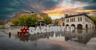 The Gaziantep city logo stands in the foreground with the historic Gaziantep Castle overlooking the city in Gaziantep, southeastern Türkiye, Nov. 16, 2018. (Shutterstock Photo)