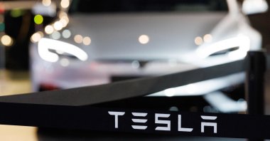 This photograph shows the logo of U.S. automobile manufacturer Tesla next to a Tesla car during a press opening of the 102th edition of the Brussels Motor Show at Brussels Expo, Brussels, Belgium, Jan. 9, 2026. (AFP Photo)