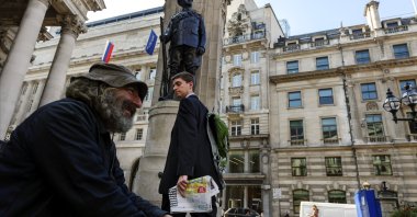 A worker in a jacket and tie glances at a beggar outside the Royal Exchange in London's financial district, known as the City, which now houses luxury shops, U.K., April 15, 2016. (Getty Images Photo)