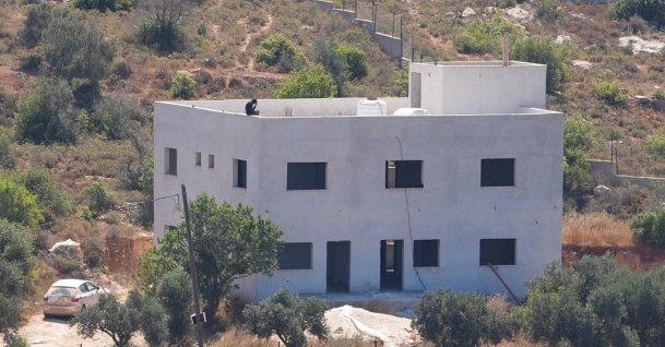 An Israeli settler sits on the roof of the Palestinian Salameh family's house, which was taken over by Israeli settlers in the village of Jalud, West Bank, Palestine, July 2, 2026. (Reuters Photo)