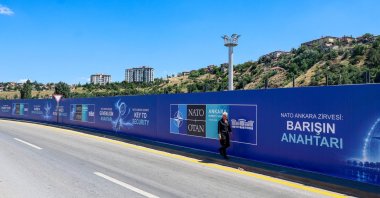 A local resident walks past billboards with the slogans “Key to Peace,” “Key to Security” and “Shared Future in Peace,” displayed along the boulevard on the protocol route ahead of the NATO summit, Ankara, June 26, 2026. (AFP Photo)