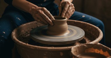 A close up of hands skillfully shaping wet clay on a spinning pottery wheel. (Shutterstock Photo)