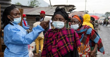 A health worker takes the temperature of a woman passing through the Kanyaruchinya checkpoint, as authorities and aid agencies intensify efforts to contain a new Ebola outbreak, Goma, the Democratic Republic of the Congo, May 20, 2026. (Retuers Photo)