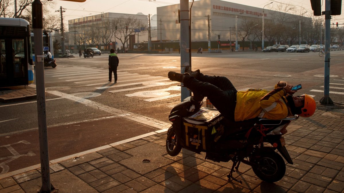 A delivery driver looks at this phone as he rests on his electric bike in Beijing, China, Jan. 25, 2020. (Reuters Photo)