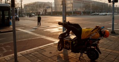A delivery driver looks at this phone as he rests on his electric bike in Beijing, China, Jan. 25, 2020. (Reuters Photo)